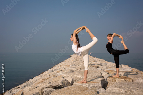 Beautiful young women practicing yoga on the beach. Natarajasana photo