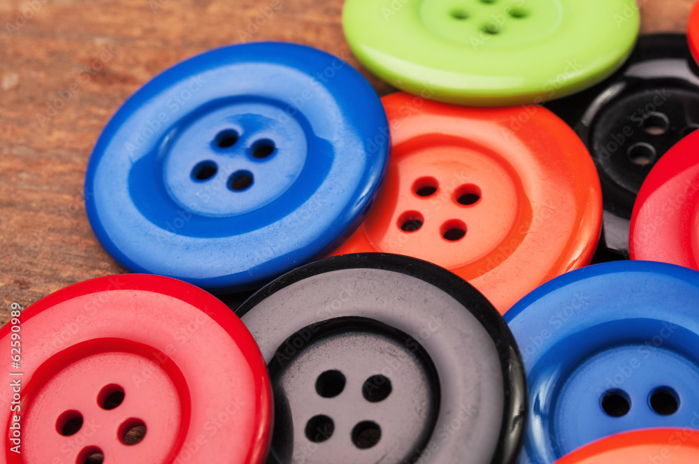 Colorful plastic buttons on a wooden surface Colorful plastic buttons on a wooden surface