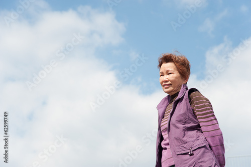 青空をバックに撮影した高齢者の女性