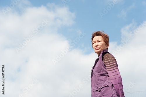 青空をバックに撮影した高齢者の女性
