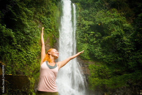 Young woman practicing yoga by the waterfall