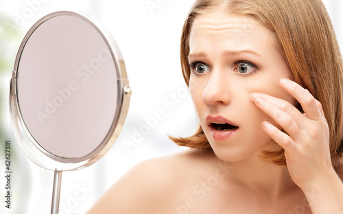 beautiful healthy woman  frightened saw in the mirror acne and w photo