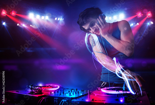 Disc jockey playing music with light beam effects on stage