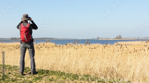 Male hiker viewing birds in wetland photo