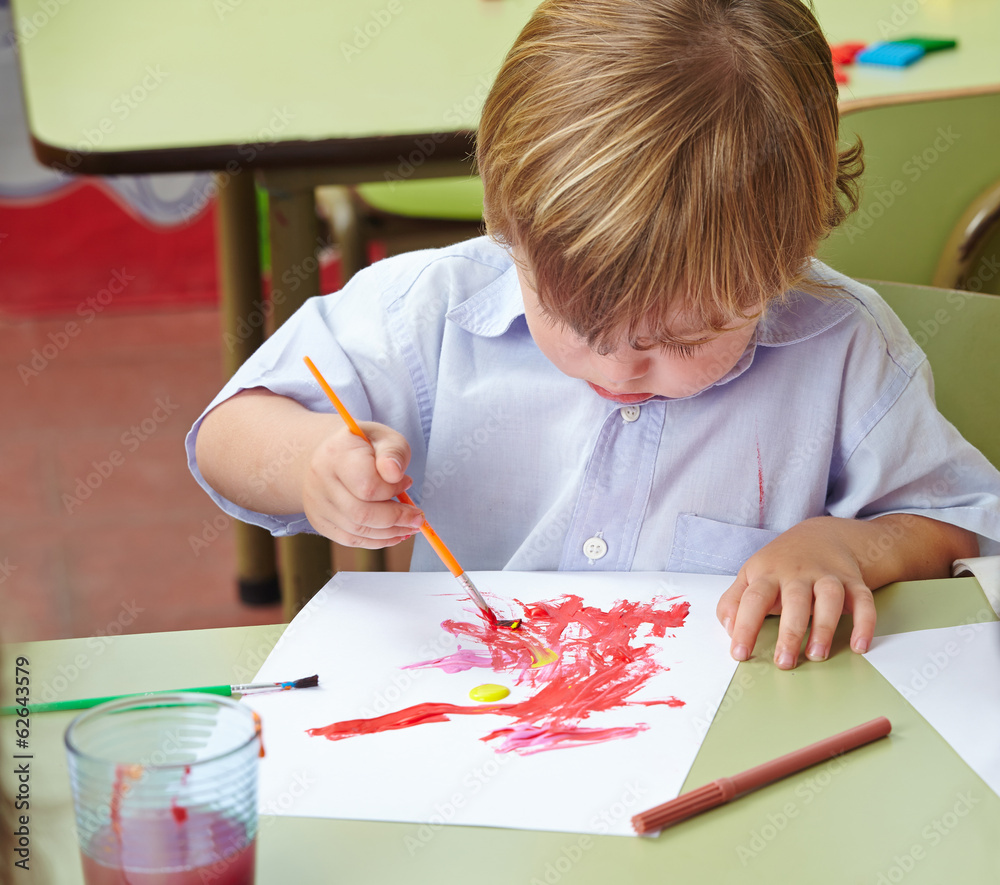Kind malt mit Pinsel und Farbe in Kita Stock Photo Adobe Stock