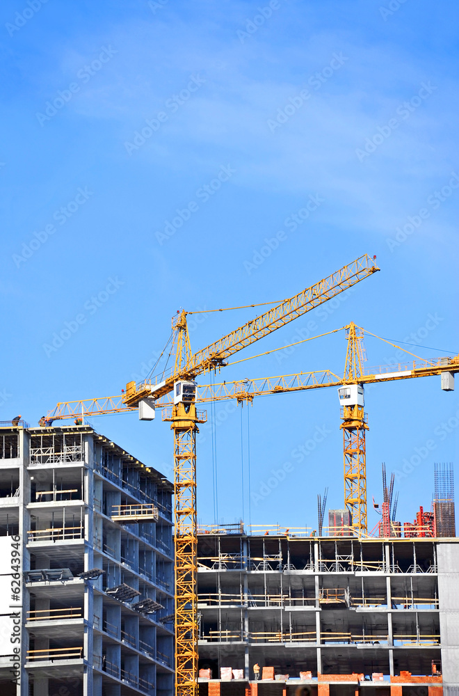 Crane and building construction site against blue sky