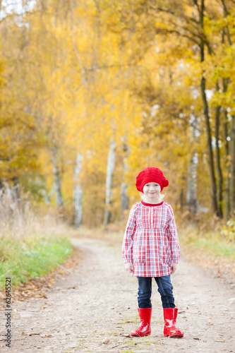 little girl wearing rubber boots in autumnal alley