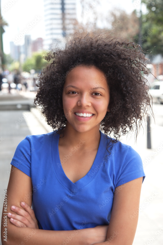 Young woman with curly hair and crossed arms in the city Young woman with curly hair and crossed arms in the city