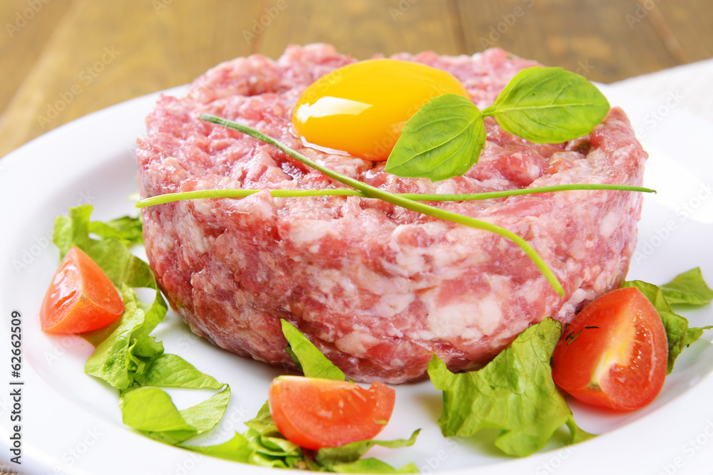 Delicious steak tartare with yolk on plate on table close-up Delicious steak tartare with yolk on plate on table close-up