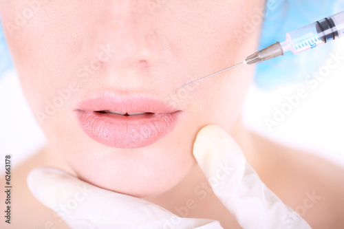 Woman in beauty clinic getting botox injection, isolated