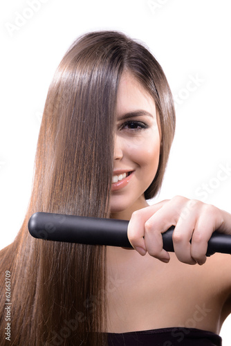 Woman doing hairstyle with hair straightener isolated on white