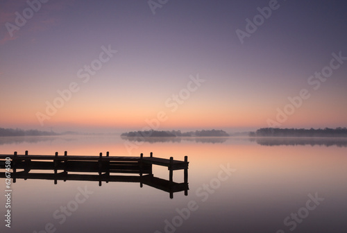Jetty at a lake during a tranquil, foggy dawn. © sanderstock