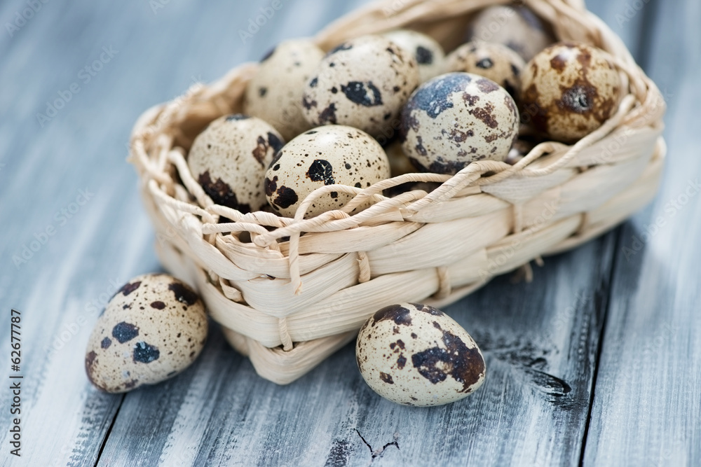 Raw quail eggs in a wicker basket over wooden background Raw quail eggs in a wicker basket over wooden background