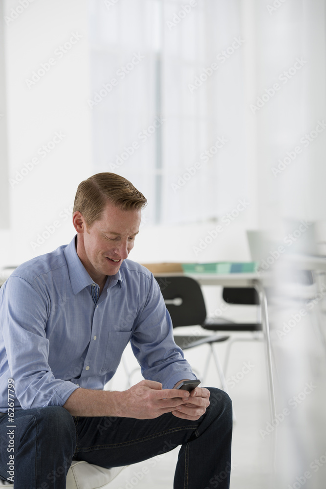 A Man Seated, Checking His Smart Phone For Messages And Texting. A Man Seated, Checking His Smart Phone For Messages And Texting.