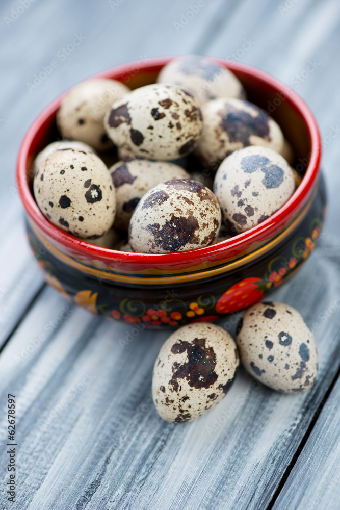 Raw quail eggs in a wooden khokhloma bowl, close-up Raw quail eggs in a wooden khokhloma bowl, close-up