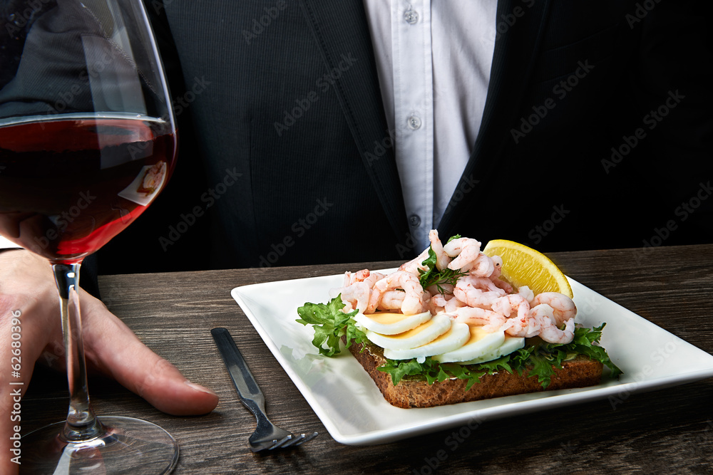 Man eating delicious shrimp salad sandwich on a plate