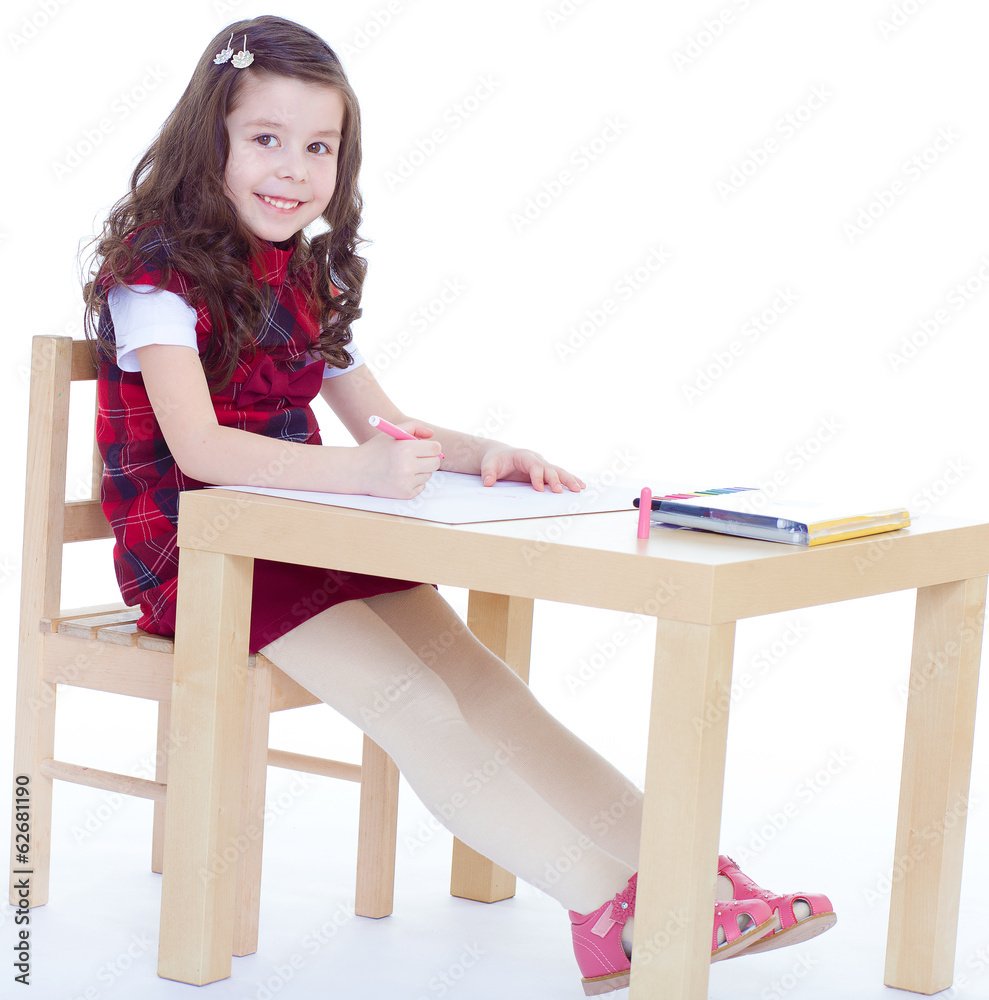 Little girl is drawing using color pencils while sitting at tabl Little girl is drawing using color pencils while sitting at tabl