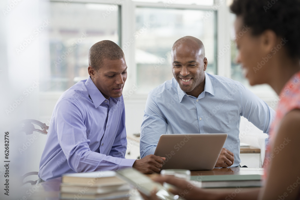 Office Life. Three People Working Around A Table, Using Digital Tablets And Laptops.