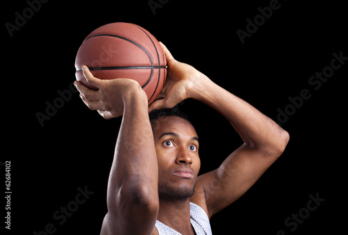 Basketball player throwing the ball against dark background