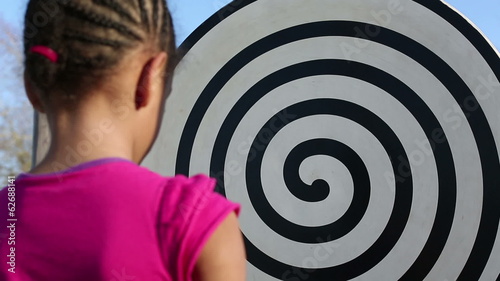 Young girl gazing at a hypnotic swirling design in a park