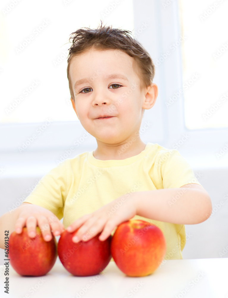 Fototapeta premium Portrait of a happy little boy with apples