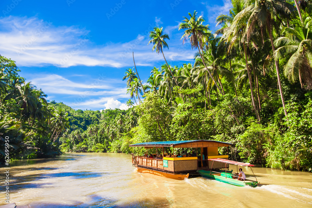Exotic cruise boat with tourists on a jungle river Loboc, Bohol