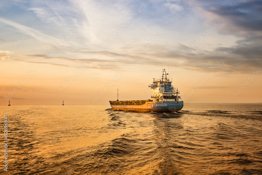 Container ship on sea road on sunset.