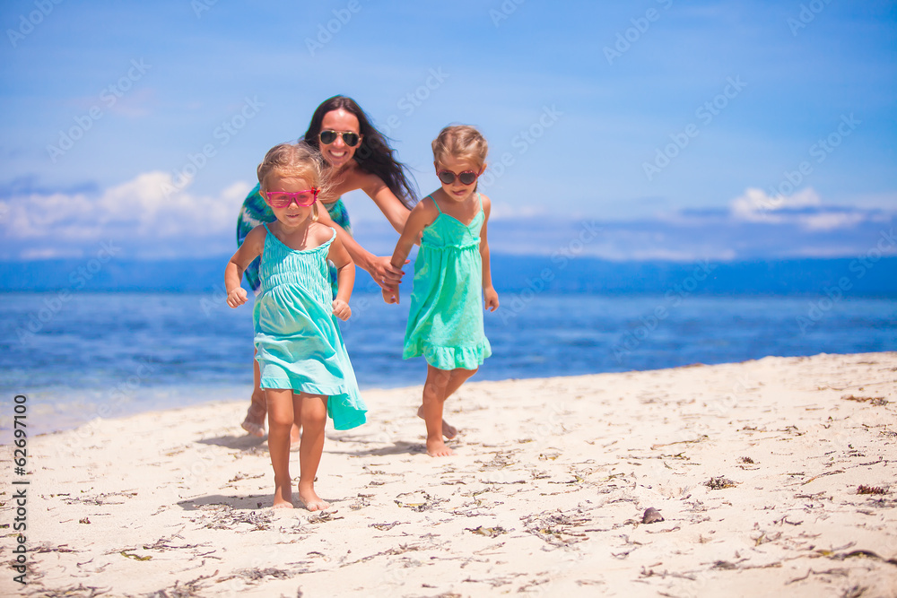 Adorable little girls and young mother have fun on tropical