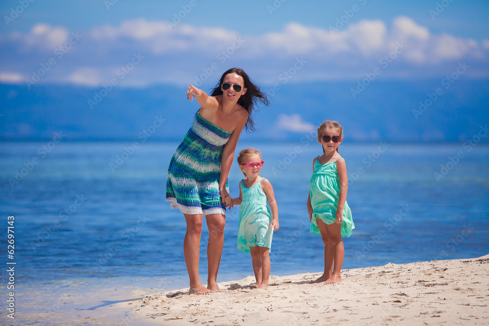 Adorable little girls and young mother walking on tropical white
