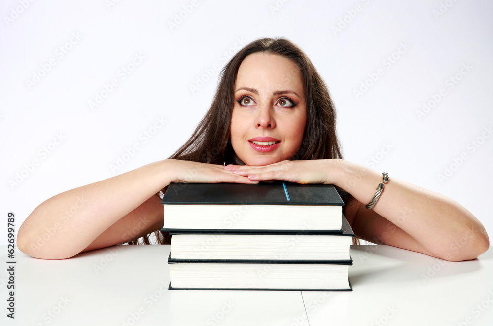 Thoughtful woman sitting on the table with books Thoughtful woman sitting on the table with books