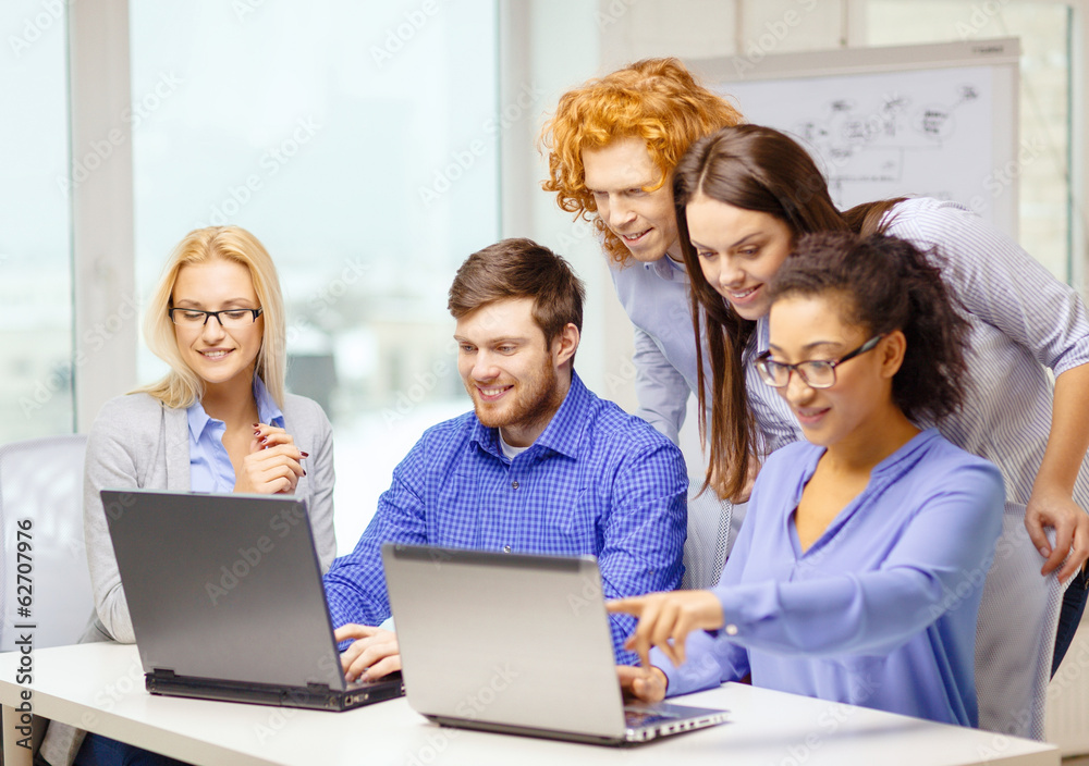 smiling team with laptop computers in office smiling team with laptop computers in office