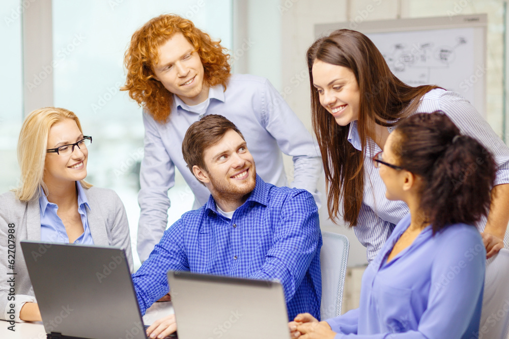 smiling team with laptop computers in office