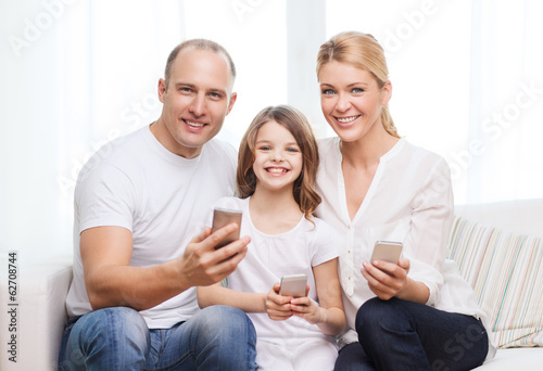 parents and little girl with smartphones at home © Syda Productions
