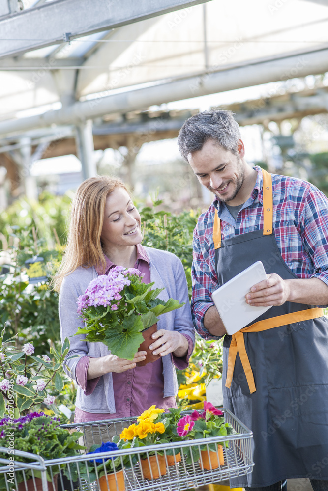 gardener using his digital tablet to advise a female client who gardener using his digital tablet to advise a female client who