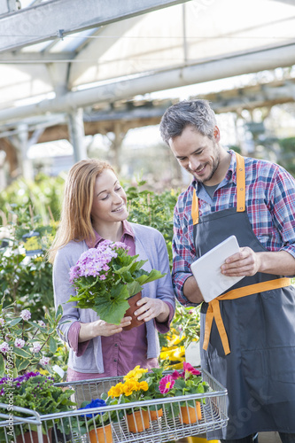 gardener using his digital tablet to advise a female client who