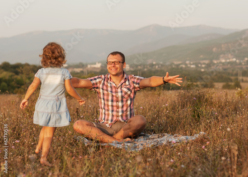 father and daughter on the field in the mountains happy