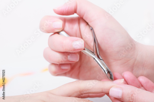 Beautician trimming cuticles of female client in beauty salon