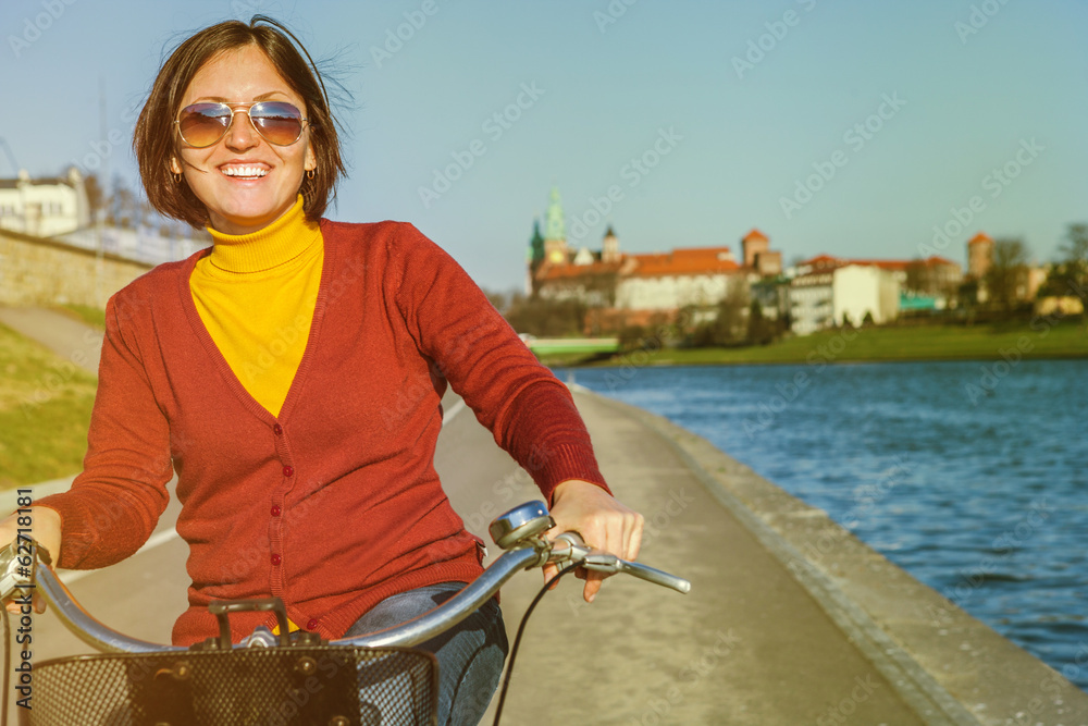 Fototapeta premium Happy woman riding by bysicle along waterfront