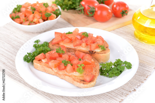 Delicious bruschetta with tomatoes on plate on table close-up