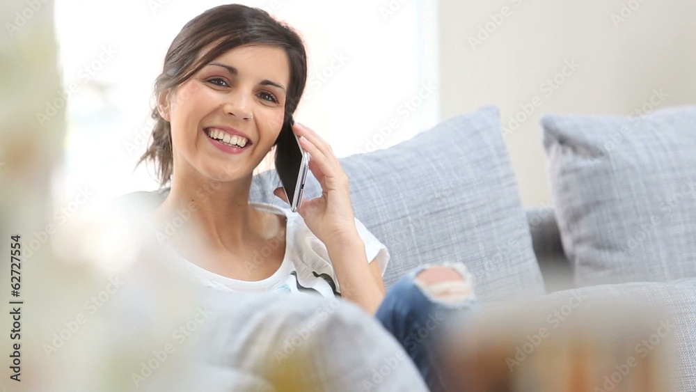 Young cheerful woman in couch talking on mobile phone Young cheerful woman in couch talking on mobile phone