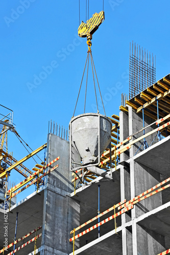 Crane lifting concrete mixer container on constructoin site photo