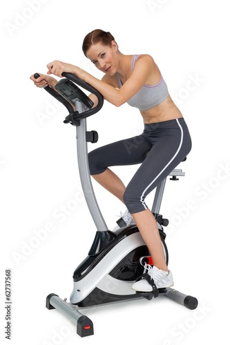 Side view of a beautiful young woman on stationary bike