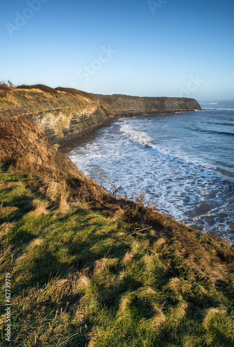 Beautiful coastal landscape at sunrise with cliffs and misty glo