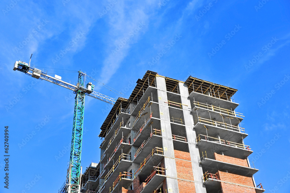 Crane and building construction site against blue sky Crane and building construction site against blue sky