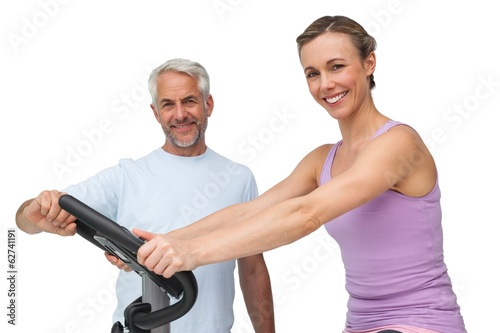 Portrait of a happy woman on stationary bike with trainer