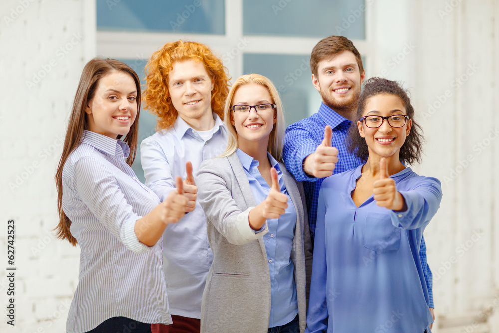 happy creative team showing thumbs up in office happy creative team showing thumbs up in office