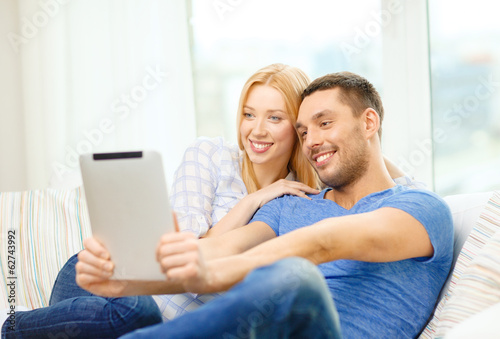 smiling happy couple with tablet pc at home