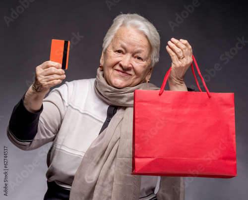 Happy old woman with shopping bags and credit card
