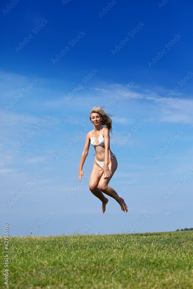 happy woman jumps in summer green field against blue sky.. happy woman jumps in summer green field against blue sky..