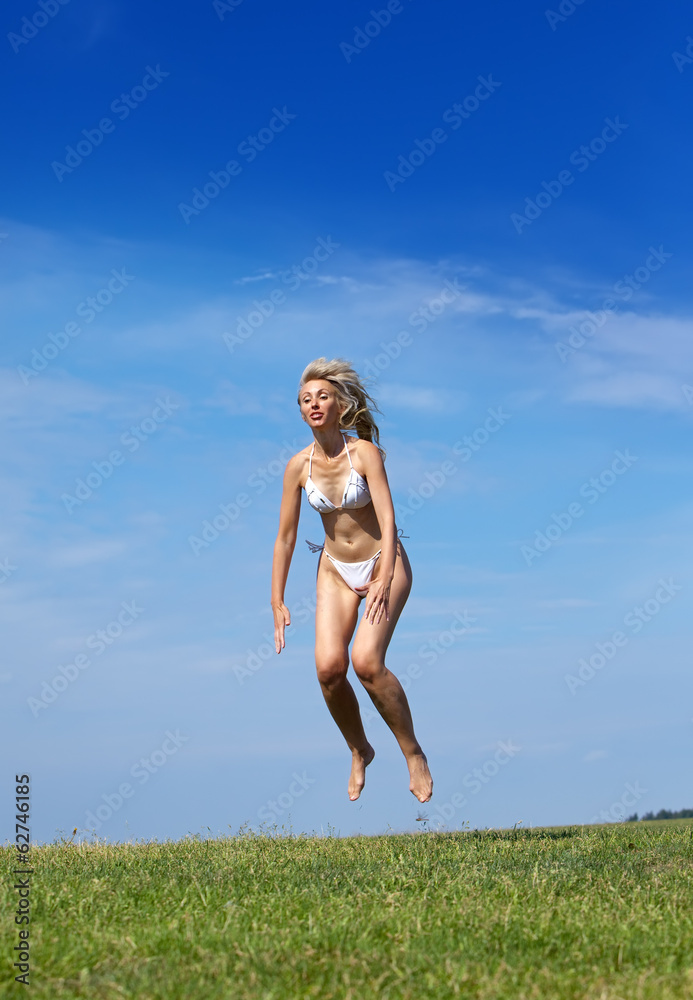 happy woman jumps in summer green field against blue sky.. happy woman jumps in summer green field against blue sky..